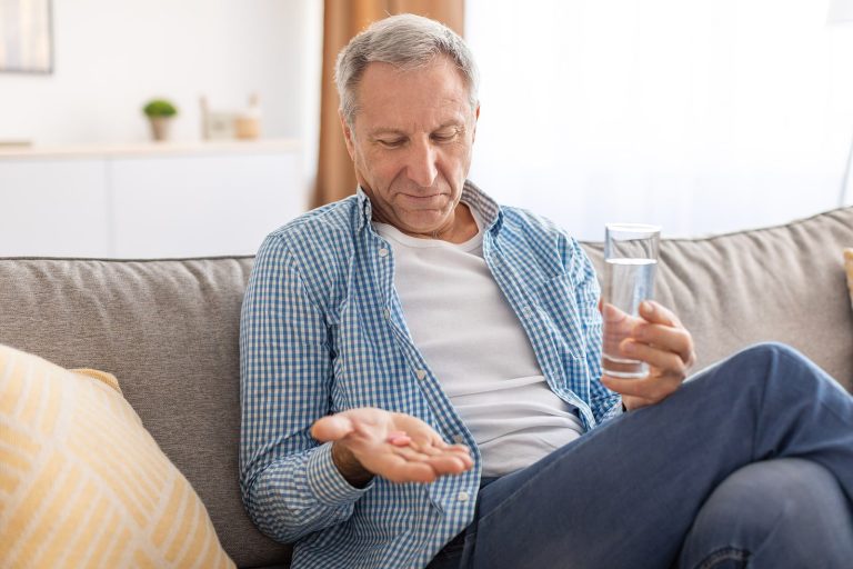 man drinking water and taking pills