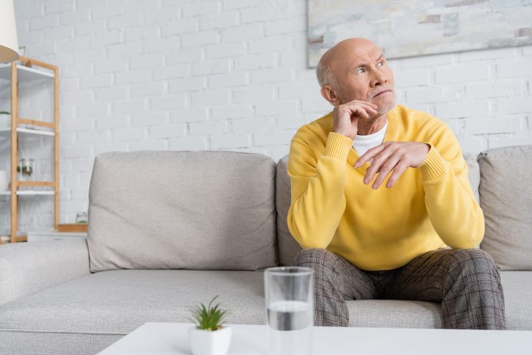 elderly man sitting next to water